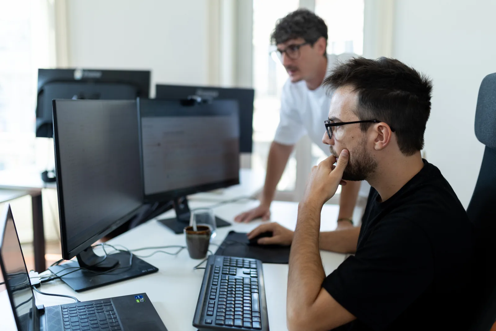Two Arkyan team members working together at their screens