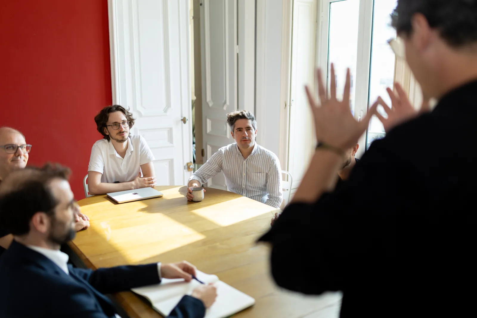 The Arkyan team gathered around a table, listening to a colleague present his ideas